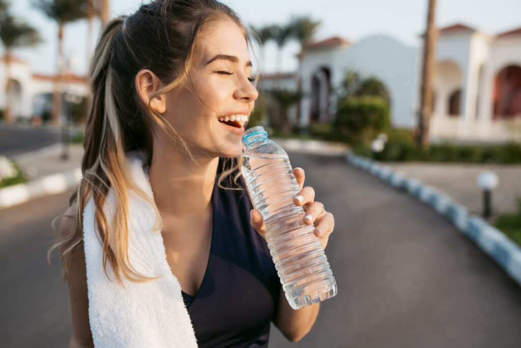 Mulher sorridente segurando garrafa de água, representando hidratação saudável para os rins
