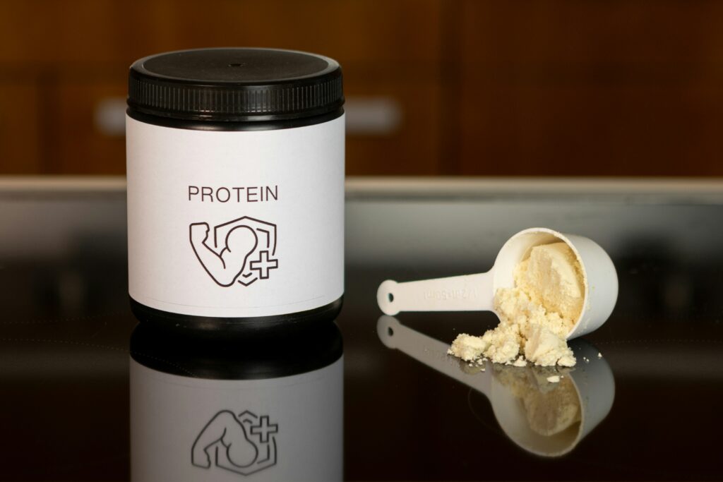 Pote de whey protein com colher dosadora e suplemento em pó