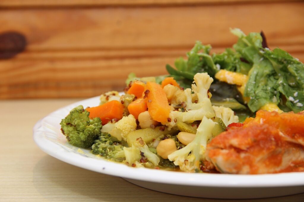 Prato com legumes cozidos, salada verde e peixe com molho, representando alimentação equilibrada após cirurgia de cálculo renal