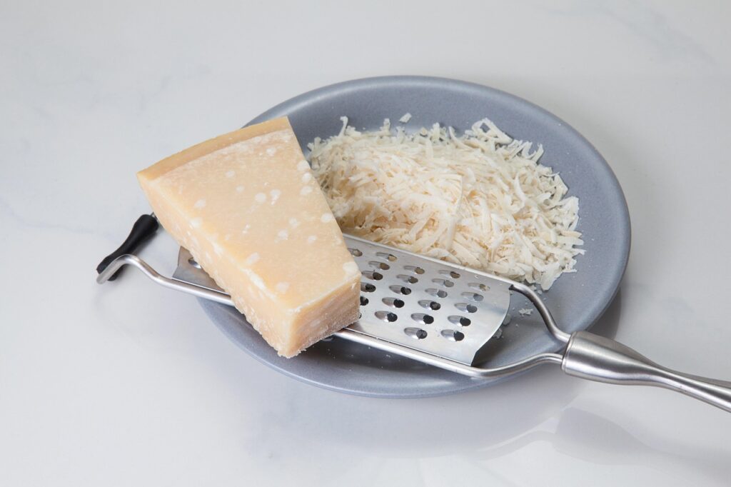 Queijo parmesão ralado e em peça sobre prato cinza